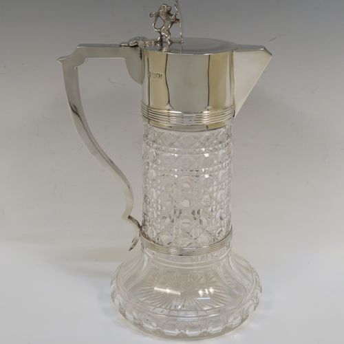 A very handsome Antique Sterling Silver and hand-cut crystal claret jug, having a plain round mount and spout with reeded borders, a plain square cross-section scroll handle attached to a security ring, a flat hinged lid with a cast rampant lion and shield finial, together with a hand-cut hobnail pattern crystal round body with straight sides and flared bottom above a flat star-cut base. This beautiful antique silver claret jug was made by Charles Boyton of London in 1912. The dimensions of this fine hand-made antique silver and crystal claret jug are height 26 cms (10.25 inches), and length 17 cms (6.75 inches).  