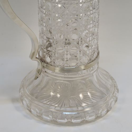 A very handsome Antique Sterling Silver and hand-cut crystal claret jug, having a plain round mount and spout with reeded borders, a plain square cross-section scroll handle attached to a security ring, a flat hinged lid with a cast rampant lion and shield finial, together with a hand-cut hobnail pattern crystal round body with straight sides and flared bottom above a flat star-cut base. This beautiful antique silver claret jug was made by Charles Boyton of London in 1912. The dimensions of this fine hand-made antique silver and crystal claret jug are height 26 cms (10.25 inches), and length 17 cms (6.75 inches).