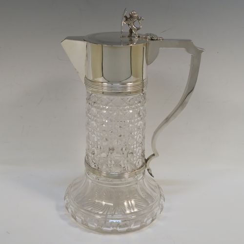 A very handsome Antique Sterling Silver and hand-cut crystal claret jug, having a plain round mount and spout with reeded borders, a plain square cross-section scroll handle attached to a security ring, a flat hinged lid with a cast rampant lion and shield finial, together with a hand-cut hobnail pattern crystal round body with straight sides and flared bottom above a flat star-cut base. This beautiful antique silver claret jug was made by Charles Boyton of London in 1912. The dimensions of this fine hand-made antique silver and crystal claret jug are height 26 cms (10.25 inches), and length 17 cms (6.75 inches).