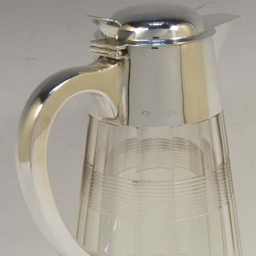 A very handsome Antique Sterling Silver and hand-cut crystal claret jug, having a plain oval mount and spout, a hinged domed lid with a thumb-piece, a plain scroll handle, together with a hand-cut round and panelled crystal body with reeded bands and star-cut base. This beautiful silver and crystal claret jug was made by John Round of Birmingham in 1919. The dimensions of this fine hand-made silver and crystal claret jug are height 24 cms (9.5 inches), and length 16.5 cms (6.5 inches).
