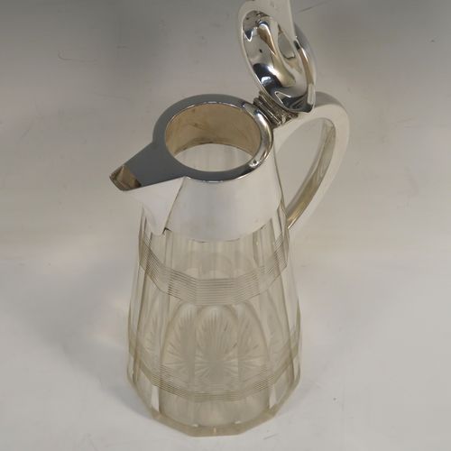 A very handsome Antique Sterling Silver and hand-cut crystal claret jug, having a plain oval mount and spout, a hinged domed lid with a thumb-piece, a plain scroll handle, together with a hand-cut round and panelled crystal body with reeded bands and star-cut base. This beautiful silver and crystal claret jug was made by John Round of Birmingham in 1919. The dimensions of this fine hand-made silver and crystal claret jug are height 24 cms (9.5 inches), and length 16.5 cms (6.5 inches).