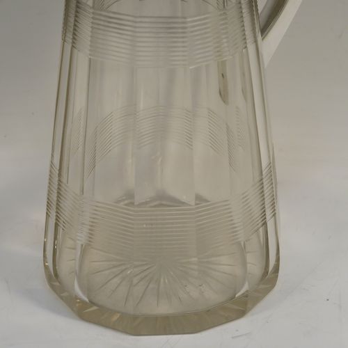 A very handsome Antique Sterling Silver and hand-cut crystal claret jug, having a plain oval mount and spout, a hinged domed lid with a thumb-piece, a plain scroll handle, together with a hand-cut round and panelled crystal body with reeded bands and star-cut base. This beautiful silver and crystal claret jug was made by John Round of Birmingham in 1919. The dimensions of this fine hand-made silver and crystal claret jug are height 24 cms (9.5 inches), and length 16.5 cms (6.5 inches).