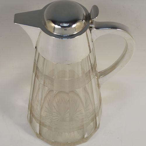 A very handsome Antique Sterling Silver and hand-cut crystal claret jug, having a plain oval mount and spout, a hinged domed lid with a thumb-piece, a plain scroll handle, together with a hand-cut round and panelled crystal body with reeded bands and star-cut base. This beautiful silver and crystal claret jug was made by John Round of Birmingham in 1919. The dimensions of this fine hand-made silver and crystal claret jug are height 24 cms (9.5 inches), and length 16.5 cms (6.5 inches).