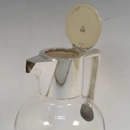 A handsome Antique Victorian Sterling Silver and hand-cut crystal claret jug, having a plain round mount, with a flat hinged lid, a plain angular handle, and a cut-off sparrow-beak style spout, together with a hand-cut crystal body sitting on a star-cut flat base. This elegant antique silver and crystal claret jug was made by Heath and Middleton of London in 1898. The dimensions of this fine hand-made antique silver and crystal claret jug are height 19.5 cms (7.75 inches), and length 13 cms (5 inches).
