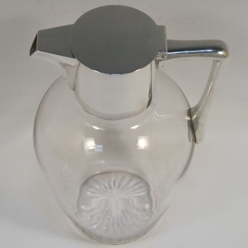 A handsome Antique Victorian Sterling Silver and hand-cut crystal claret jug, having a plain round mount, with a flat hinged lid, a plain angular handle, and a cut-off sparrow-beak style spout, together with a hand-cut crystal body sitting on a star-cut flat base. This elegant antique silver and crystal claret jug was made by Heath and Middleton of London in 1898. The dimensions of this fine hand-made antique silver and crystal claret jug are height 19.5 cms (7.75 inches), and length 13 cms (5 inches).