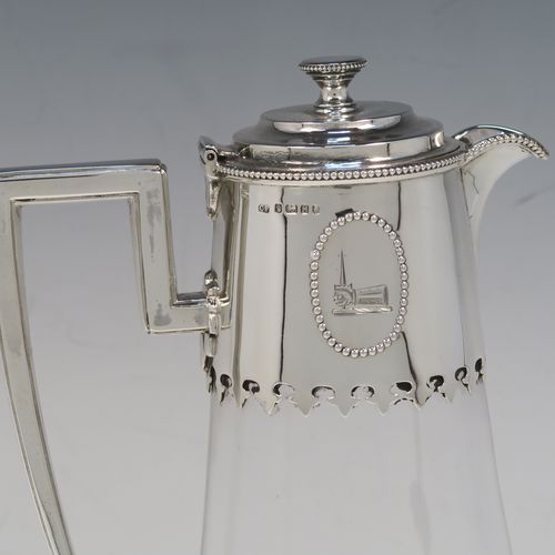 A very elegant Antique Victorian Sterling Silver and hand-cut crystal claret jug, having a plain round mount with applied bead-edged borders, a plain square cross-section side handle, a hinged stepped lid with a cast round finial, together with a hand-cut crystal round body with straight tapering sides and a tucked under belly above a pedestal foot. This handsome silver and crystal claret jug was made by Charles Favell of Sheffield in 1875. The dimensions of this fine hand-made antique silver and crystal claret jug are height 28 cms (11 inches), and length 13.5 cms (5.25 inches). Please note that this item has two oval cartouches with bead borders one of which is engraved with a part crest.