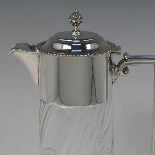 A very handsome Antique late Victorian Sterling Silver and hand-cut crystal claret jug, having a plain round mount, a hinged domed lid with a gadroon border and finial, an angular and scrolled side-handle, and a round hand-cut straight-sided body with flared base, having swirl-fluted decoration and a star-cut base. This elegant silver and crystal claret jug was made by William Hutton of Sheffield in 1901. The dimensions of this fine hand-made antique silver and crystal claret jug are height 26 cms (10.25 inches), and length 15 cms (6 inches).