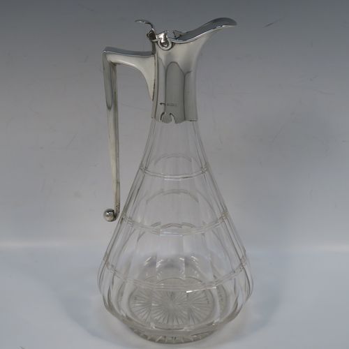 A very elegant Antique Victorian Sterling Silver and hand-cut crystal claret jug, having a plain silver mount with a hinged lid, finial, and angular side-handle, attached to a pear-drop shaped hand-cut crystal body with panelled and reeded decoration, and sitting on a star-cut flat base. This handsome silver and crystal claret jug was made by John Grinsell of Birmingham in 1912. The dimensions of this fine hand-made antique silver and crystal claret jug are height 24 cms (9.5 inches), and diameter of main body 12 cms (4.75 inches).  