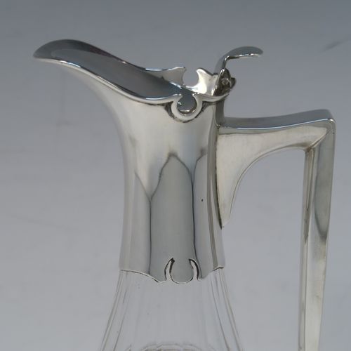 A very elegant Antique Victorian Sterling Silver and hand-cut crystal claret jug, having a plain silver mount with a hinged lid, finial, and angular side-handle, attached to a pear-drop shaped hand-cut crystal body with panelled and reeded decoration, and sitting on a star-cut flat base. This handsome silver and crystal claret jug was made by John Grinsell of Birmingham in 1912. The dimensions of this fine hand-made antique silver and crystal claret jug are height 24 cms (9.5 inches), and diameter of main body 12 cms (4.75 inches).