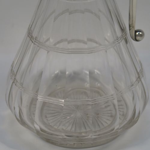 A very elegant Antique Victorian Sterling Silver and hand-cut crystal claret jug, having a plain silver mount with a hinged lid, finial, and angular side-handle, attached to a pear-drop shaped hand-cut crystal body with panelled and reeded decoration, and sitting on a star-cut flat base. This handsome silver and crystal claret jug was made by John Grinsell of Birmingham in 1912. The dimensions of this fine hand-made antique silver and crystal claret jug are height 24 cms (9.5 inches), and diameter of main body 12 cms (4.75 inches).