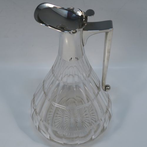 A very elegant Antique Victorian Sterling Silver and hand-cut crystal claret jug, having a plain silver mount with a hinged lid, finial, and angular side-handle, attached to a pear-drop shaped hand-cut crystal body with panelled and reeded decoration, and sitting on a star-cut flat base. This handsome silver and crystal claret jug was made by John Grinsell of Birmingham in 1912. The dimensions of this fine hand-made antique silver and crystal claret jug are height 24 cms (9.5 inches), and diameter of main body 12 cms (4.75 inches).