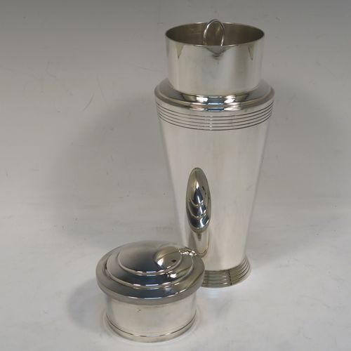 A very stylish and handsome Silver-Plated Art Deco cocktail shaker, having a plain round body with tapering sides and reeded decoration, a pull-off round stepped lid, and a central removable strainer section with loop handle. This elegant silver-plated cocktail shaker was made by Mappin and Webb of Sheffield in ca. 1930. The dimensions of this fine hand-made silver plated cocktail shaker are height 23 cms (9 inches), and diameter at widest point is 9 cms (3.5 inches).