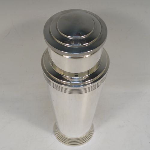 A very stylish and handsome Silver-Plated Art Deco cocktail shaker, having a plain round body with tapering sides and reeded decoration, a pull-off round stepped lid, and a central removable strainer section with loop handle. This elegant silver-plated cocktail shaker was made by Mappin and Webb of Sheffield in ca. 1930. The dimensions of this fine hand-made silver plated cocktail shaker are height 23 cms (9 inches), and diameter at widest point is 9 cms (3.5 inches).
