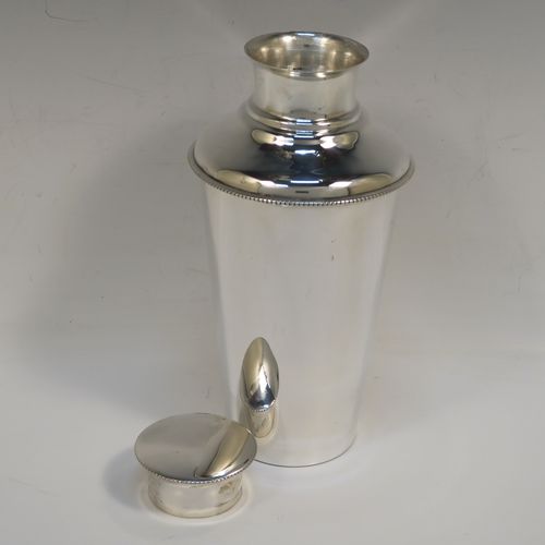 A very handsome Sterling Silver Art Deco cocktail shaker, having a plain round body with tapering sides, with a pull-off lid and interior strainer section, and a bead edge to the main body and lid. This elegant silver cocktail shaker was made by Synyer and Beddoes of Birmingham in 1939. The dimensions of this fine hand-made silver cocktail shaker are height 19 cms (7.5 inches), diameter at widest point 9.5 cms (3.75 inches), and it weighs approx. 329g (10.6 troy ounces).