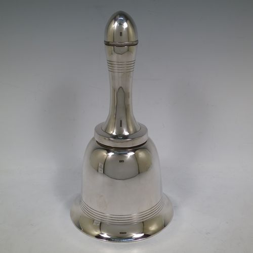 A very unusual novelty Silver-Plated cocktail shaker in the shape of a table bell, having a plain round body with hand-engraved reeded decoration, with a screw-off hollow handle attached to the main body, and a screw-off terminal lid with cork seal covering a pouring strainer section. Made by Edward and Sons of Glasgow, Scotland, in ca. 1930. The dimensions of this fine hand-made silver plated table bell cocktail shaker are height 28 cms (11 inches), diameter at base 15 cms (6 inches).    