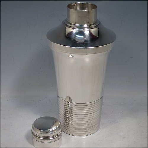 A very handsome Art Deco style Silver-Plated cocktail shaker, having a plain round body with tapering sides, with a pull-off lid and a strainer section, together with a lower band of hand-chased reeded decoration. Made in ca. 1930. The dimensions of this fine hand-made silver plated cocktail shaker are height 21 cms (8.25 inches), diameter at widest point 10 cms (4 inches).