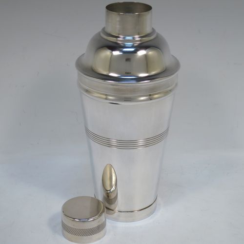 A very stylish and handsome Silver-Plated Art Deco cocktail shaker, having a plain round body with tapering sides, with reeded and engine-turned decoration, a pull-off round lid, and a central removable strainer section. Made in ca. 1930. The dimensions of this fine hand-made silver plated cocktail shaker are height 21.5 cms (8.5 inches), and diameter at widest point is 9 cms (3.5 inches).  
