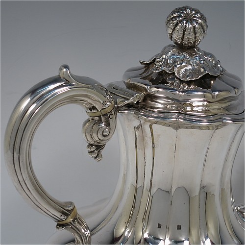 A very handsome Antique Victorian Sterling Silver hand-chased coffee pot, having a round hand-chased baluster body with melon-style fluting, a hinged lid with melon fluting and original cast floral finial, an insulated silver handle, a fluted spout, and all sitting on four shell and scroll feet. Made by the Savoury Brothers of London in 1846. The dimensions of this fine hand-made antique silver coffee pot are height 26 cms (10.25 inches), length 26 cms (10.25 inches), and it weighs approx. 862g (28 troy ounces).