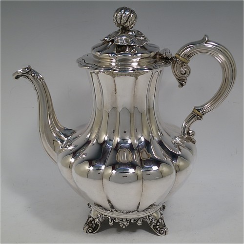 A very handsome Antique Victorian Sterling Silver hand-chased coffee pot, having a round hand-chased baluster body with melon-style fluting, a hinged lid with melon fluting and original cast floral finial, an insulated silver handle, a fluted spout, and all sitting on four shell and scroll feet. Made by the Savoury Brothers of London in 1846. The dimensions of this fine hand-made antique silver coffee pot are height 26 cms (10.25 inches), length 26 cms (10.25 inches), and it weighs approx. 862g (28 troy ounces).