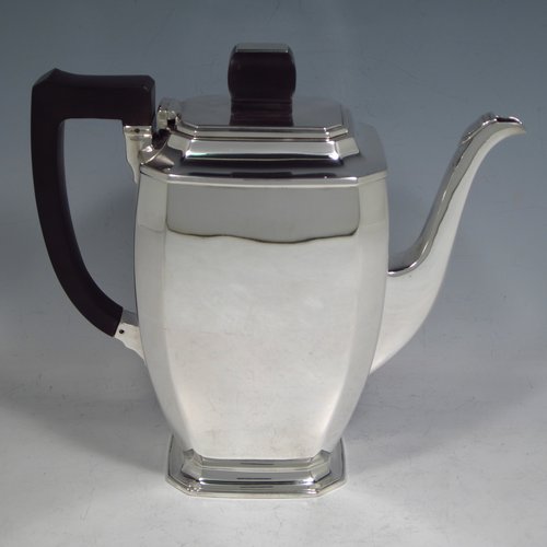 A Sterling silver Art Deco style coffee pot, having very plain panelled body with tapering sides, a wooden handle, a hinged lid with matching finial, and all sitting on a collet foot. Made by Mappin & Webb of Sheffield in 1950. The dimensions of this fine hand-made silver coffee pot are length 20 cms (8 inches), height 19 cms (7.5 inches), and it weighs approx. 600g (19.4 troy ounces).   