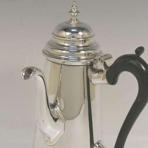 A large and very handsome Antique Edwardian Sterling Silver George II style side-handled coffee pot, having a plain round body with straight tapering sides, a hinged domed lid with cast urn-shaped finial, a curved and panelled spout, a hand-carved wooden scroll handle, and all sitting on a flat base. This elegant silver coffee-pot was made by D. and J. Welby of London in 1910. The dimensions of this fine hand-made antique silver side-handled coffee pot are length 13.5 cms (5.25 inches), height 23.5 cms (9.25 inches), and it weighs approx. 750g (24 troy ounces).