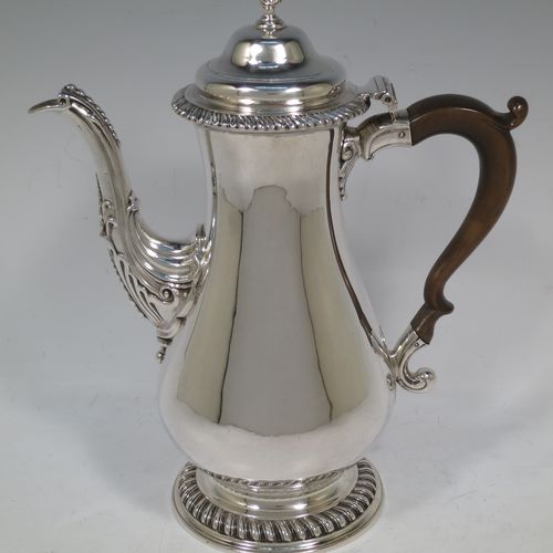 A very handsome Antique Georgian Sterling Silver coffee pot, having a plain round bellied body, with applied gadroon borders, a wooden scroll handle, a flame knop finial, and anthemion leaf decorated spout. Made by William Grundy London in 1775. The dimensions of this fine hand-made antique silver coffee pot are height 26 cms (10.25 inches), length 22 cms (8.75 inches), and it weighs approx. 800g (25.8 troy ounces).    