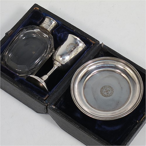 An Antique Victorian silver-plated three-piece travelling communion set consisting of a chalice, paten, and wine bottle. The chalice having a plain round body, a gold-gilt interior, and sitting on a pedestal foot. The paten having a round body with a reeded border, and sitting on a collet foot. The wine bottle having a plain round screw-off lid, an original glass stopper, and the glass body with hand-cut panelled decoration. The chalice and paten are engraved with a Christogram, and all sit in their original blue velvet-lined presentation box. Made in ca. 1890. The dimensions of this fine hand-made antique silver plated travelling communion set are height of chalice 7.5 cms (3 inches), diameter of paten 8 cms (3 inches), and height of wine bottle 8.5 cms (3.3 inches).