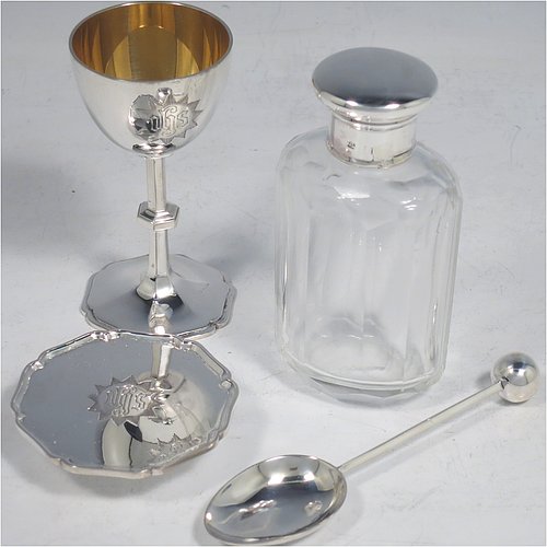 A Sterling Silver four-piece travelling communion set consisting of chalice, paten, spoon, and wine bottle. The chalice having a plain round body, a gold-gilt interior, and sitting on a hexagonal pedestal foot. The paten having a hexagonal body with an applied shaped border, and sitting on a collet foot. The wine bottle having a plain round screw-off lid, a cork seal, and the glass body with hand-cut panelled decoration. The anointing spoon having a plain oval bowl and ball finial. Both the chalice and paten are engraved with a Christogram. All sitting in its original purple satin and velvet-lined presentation box. Made by A. R. Mowbray & Co. Ltd., of London in 1930. The dimensions of this fine hand-made silver travelling communion set are height of chalice 8 cms (3.25 inches), diameter of paten 5.5 cms (2.25 inches), length of spoon 10 cms (4 inches), and with a total weight of approx. 125g (4 troy ounces).    