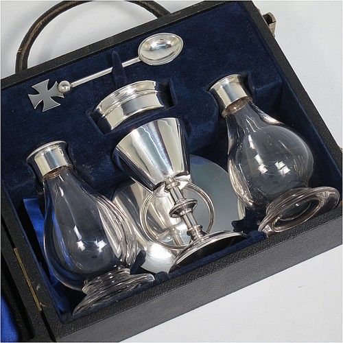 A Sterling Silver six-piece travelling communion set consisting of chalice, paten, water, and wine bottles, a wafer pyx box, and an anointing spoon. The chalice having a plain round body with tapering sides, and sitting on a round pedestal foot. The paten and pyx box having plain round bodies. The wine and water bottles having plain round screw-off lids, cork seals, and hand-cut crystal bodies. All sitting in their original dark blue satin and velvet-lined presentation box, which also has a concealed compartment for sacramental cloth and wafers. All made by H. F. and Co. Ltd., of London in 1966. The dimensions of this fine hand-made silver travelling communion set are height of chalice 8.5 cms (3.3 inches), diameter of paten 8.5 cms (3.3 inches), and with a total weight of approx. 155g (5 troy ounces). Please note that there is slight damage to the box interior, but every item is still held securely.