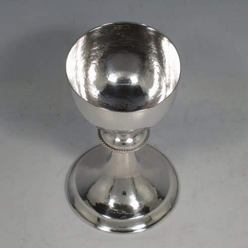 A Sterling Silver small communion chalice, having a plain round body, with a hand-hammered or finish, a central baluster with an applied rope-twist border, and sitting on a pedestal foot. Made by Greenwood & Watts of London in 1926. The dimensions of this fin hand-made silver communion cup are height 11.5 cms (4.5 inches), diameter of base 7 cms (2.75 inches), and it weighs approx. 107g (3.4 troy ounces).