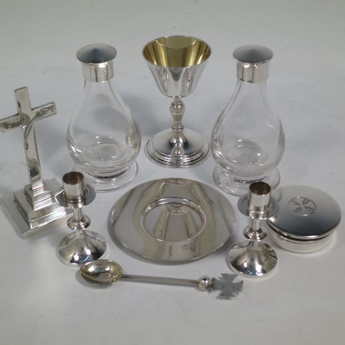 A rare and complete Sterling Silver full eight-piece travelling communion set consisting of chalice, paten, water, and wine bottles, a wafer pyx box, an anointing spoon, a pair of candle taper-sticks, and a table altar cross. All in a very plain style beautifully hand-made. The wine and water bottles having plain round screw-off lids, cork seals, and hand-cut crystal bodies. All sitting in their original dark blue velvet-lined presentation box, which also has a concealed compartment for sacramental cloth and wafers. All made by Hurst,Franklin & Co. Ltd., of London in 1963/64. The dimensions of this fine hand-made silver travelling communion set are height of altar cross 10 cms (4 inches), diameter of paten 8.5 cms (3.3 inches), and with a total weight of approx. 405g (13 troy ounces).