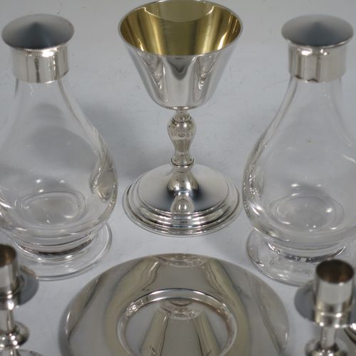 A rare and complete Sterling Silver full eight-piece travelling communion set consisting of chalice, paten, water, and wine bottles, a wafer pyx box, an anointing spoon, a pair of candle taper-sticks, and a table altar cross. All in a very plain style beautifully hand-made. The wine and water bottles having plain round screw-off lids, cork seals, and hand-cut crystal bodies. All sitting in their original dark blue velvet-lined presentation box, which also has a concealed compartment for sacramental cloth and wafers. All made by Hurst,Franklin & Co. Ltd., of London in 1963/64. The dimensions of this fine hand-made silver travelling communion set are height of altar cross 10 cms (4 inches), diameter of paten 8.5 cms (3.3 inches), and with a total weight of approx. 405g (13 troy ounces).