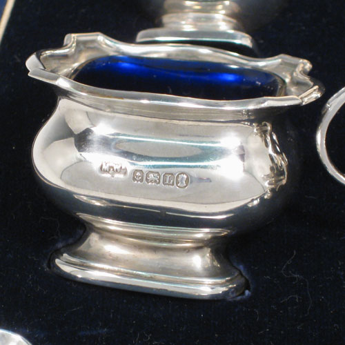 Sterling silver six-piece baluster condiment set in original satin and velvet-lined presentation box, having two open salts and two covered mustard pots all with blue-glass liners, two pepper pots, and four silver condiment spoons. Made by mappin and Webb of Birmingham in 1935. Height of pepper pots 8 cms (3 inches), length of mustard pots 7 cms (2.75 inches). Total weight approx. 232g (7.5 troy ounces).    