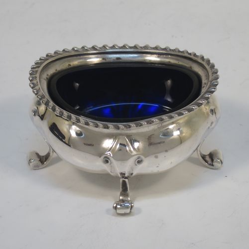 A handsome and large Antique Edwardian Sterling Silver seven-piece condiment service, consisting of a mustard pot with hinged lid and blue-glass liner, four salt cellars with blue-glass liners, and two pepper pots with pull-off lids, all with scroll fluted bellied bodies and sitting four scroll feet, and all fitted into their original dark blue satin and velvet-lined red presentation box. Made by James Round of London in 1903. The dimensions of this fine hand-made condiment service are height of pepper pot 9 cms (3.5 inches), length of mustard pot 9 cms (3.5 inches), and with a total weight of approx. 353g (11.4 troy ounces).