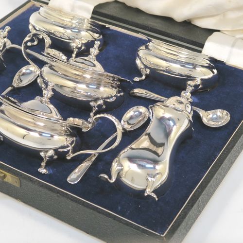 A handsome and large Antique Edwardian Silver Plated six-piece condiment service in a Chippendale style, consisting of two mustard pots with hinged lids and blue-glass liners, two salt cellars with blue-glass liners, two pepper pots with pull-off lids, all with bellied bodies and sitting on four scroll feet, together with two salt spoons and two mustard spoons, and all fitted into their original cream satin and and dark blue velvet-lined presentation box. This beautiful antique silver-plated condiment service was made by Walker and Hall of Sheffield in ca. 1910. The dimensions of this fine hand-made antique condiment service are height of pepper pots 10 cms (4 inches), length of mustard pots 10 cms (4 inches), and length of salt cellars 7.5 cms (3 inches).
