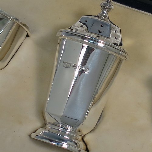A Sterling Silver three-piece condiment set, in a panelled Art Deco style, and consisting of a pepper pot, open salt cellar, and covered mustard pot, the latter two items with original blue glass liners, and sitting on pedestal feet, the pepper pot with a pull-off lid with finial, and together with two silver condiment spoons, and all in their original cream satin & velvet-line presentation box. Made by Mappin & Webb of Birmingham in 1930 (the spoons being made in 1902). The dimensions of this fine hand-made silver condiment service are height of pepper pot 7 cms (2.75 inches), length of mustard pot 6.5 cms (2.5 inches), and the total weight is approx. 89g (2.9 troy ounces).