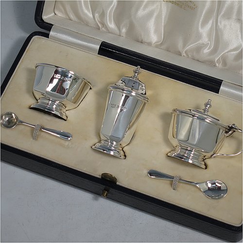 A Sterling Silver three-piece condiment set, in a panelled Art Deco style, and consisting of a pepper pot, open salt cellar, and covered mustard pot, the latter two items with original blue glass liners, and sitting on pedestal feet, the pepper pot with a pull-off lid with finial, and together with two silver condiment spoons, and all in their original cream satin & velvet-line presentation box. Made by Mappin & Webb of Birmingham in 1930 (the spoons being made in 1902). The dimensions of this fine hand-made silver condiment service are height of pepper pot 7 cms (2.75 inches), length of mustard pot 6.5 cms (2.5 inches), and the total weight is approx. 89g (2.9 troy ounces).