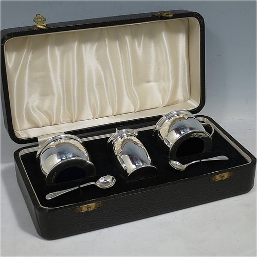 A Sterling Silver three-piece condiment set, in a very plain round bellied style, and consisting of two condiment spoons, a pepper pot, open salt cellar, and covered mustard pot, the latter two items with original blue glass liners, and all in their original cream satin and black velvet-lined presentation box. Made by Israel Sigmund Greenberg of Birmingham in 1939. The dimensions of this fine hand-made silver condiment service are height of pepper pot 7 cms (2.75 inches), length of mustard pot 7 cms (2.75 inches), and the total weight is approx. 88g (2.8 troy ounces).    