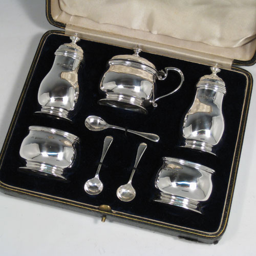 Sterling silver condiment service, consisting of a mustard pot with hinged lid and blue glass liner, two salt cellars with blue glass liners, two pepper pots with pull-off lids, all with plain baluster bodies sitting on collet feet, together with their original condiment spoons, and all fitted into their original satin and velvet-lined presentation box. Made by the Adies Brothers of Birmingham in 1935. Height of pepper pot 10 cms (4 inches), length of mustard pot 9 cms (3.5 inches). Total weight approx. 395g (12.7 troy ounces).