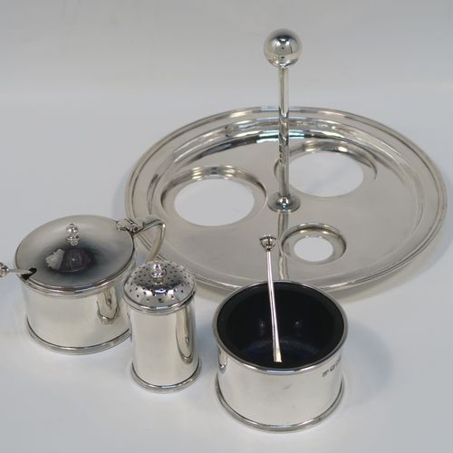 A very elegant and unusual Arts and Crafts style Sterling Silver three-piece condiment, with hand-hammered straight-sided round bodies, consisting of an open salt cellar with a blue glass liner and original spoon, a pepper pot with pull-off lid, a mustard pot with blue glass liner, hinged lid, and original spoon, an all sitting on a circular plate with carrying handle. This handsome silver condiment service was all made by the London Guild of Handicrafts in 1989. The dimensions of this fine hand-made Arts and Crafts style silver condiment set are diameter of holding plate 19 cms (7.5 inches), diameter of mustard and salt pots 6 cms (2.3 inches), height of pepper pot 7 cms (2.75 inches), and with a total weight of approx. 598g (19.3 troy ounces).   