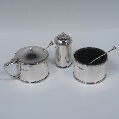 A very elegant and unusual Arts and Crafts style Sterling Silver three-piece condiment, with hand-hammered straight-sided round bodies, consisting of an open salt cellar with a blue glass liner and original spoon, a pepper pot with pull-off lid, a mustard pot with blue glass liner, hinged lid, and original spoon, an all sitting on a circular plate with carrying handle. This handsome silver condiment service was all made by the London Guild of Handicrafts in 1989. The dimensions of this fine hand-made Arts and Crafts style silver condiment set are diameter of holding plate 19 cms (7.5 inches), diameter of mustard and salt pots 6 cms (2.3 inches), height of pepper pot 7 cms (2.75 inches), and with a total weight of approx. 598g (19.3 troy ounces).   