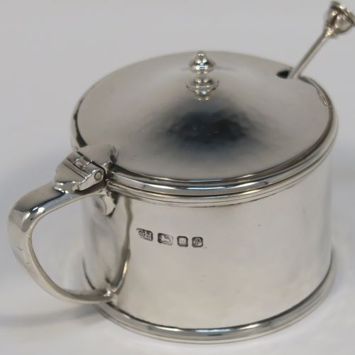 A very elegant and unusual Arts and Crafts style Sterling Silver three-piece condiment, with hand-hammered straight-sided round bodies, consisting of an open salt cellar with a blue glass liner and original spoon, a pepper pot with pull-off lid, a mustard pot with blue glass liner, hinged lid, and original spoon, an all sitting on a circular plate with carrying handle. This handsome silver condiment service was all made by the London Guild of Handicrafts in 1989. The dimensions of this fine hand-made Arts and Crafts style silver condiment set are diameter of holding plate 19 cms (7.5 inches), diameter of mustard and salt pots 6 cms (2.3 inches), height of pepper pot 7 cms (2.75 inches), and with a total weight of approx. 598g (19.3 troy ounces).   