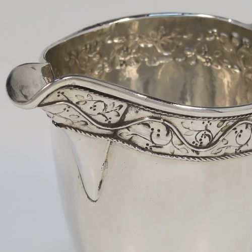 A beautiful Sterling Silver Arts and Crafts style cream or milk jug, having a round body with hand-hammered decoration, with an applied and hand-chased top band of floral work, with a cast rounded side-handle, and all sitting on a spreading round pedestal foot with applied rope-twist borders. This fantastic silver milk or cream jug was made by Harold Edwin Landon of Chester in 1933. The dimensions of this fine hand-made Arts and Crafts jug are height 11.5 cms (4.5 inches), length 14 cms (5.5 inches), and with a weight of approx. 195g (6.3 troy ounces).