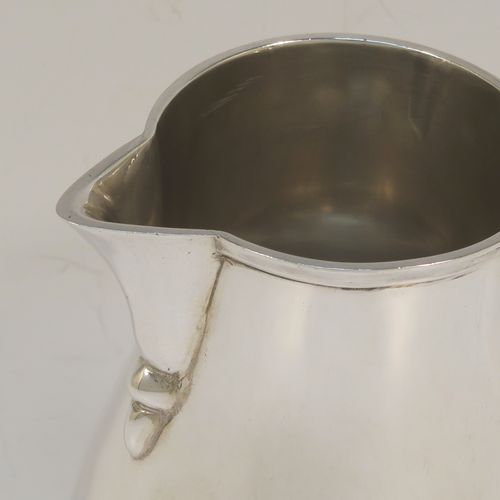 A large and handsome Sterling Silver cream jug, in a George I Sparrow-Beak style with a plain round bellied body, an applied reeded top border, a scroll handle with an anthemion thumb-piece, a sparrow-beak spout, and sitting on a collet foot. This beautiful cream jug was made by Alfred Ernest Neighbour of London in 1937. The dimensions of this fine hand-made and large silver cream jug are height 10.5 cms (4.25 inches), length 10 cms (4 inches), and it weighs approx. 181g (5.8 troy ounces).