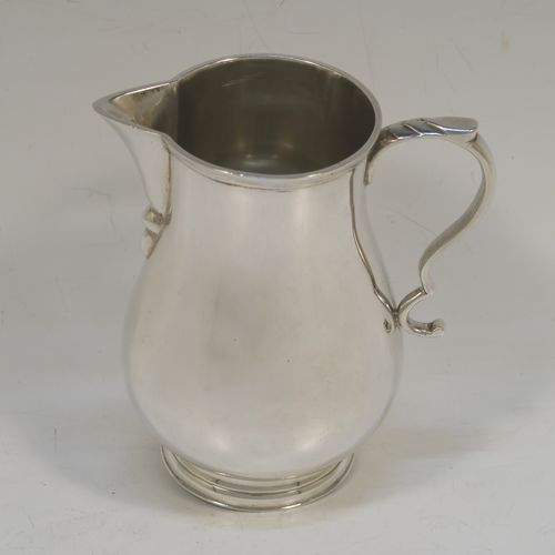 A large and handsome Sterling Silver cream jug, in a George I Sparrow-Beak style with a plain round bellied body, an applied reeded top border, a scroll handle with an anthemion thumb-piece, a sparrow-beak spout, and sitting on a collet foot. This beautiful cream jug was made by Alfred Ernest Neighbour of London in 1937. The dimensions of this fine hand-made and large silver cream jug are height 10.5 cms (4.25 inches), length 10 cms (4 inches), and it weighs approx. 181g (5.8 troy ounces).