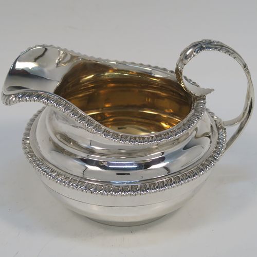 A very handsome Antique Georgian Sterling Silver large cream jug, having a plain round bellied body with applied gadroon borders, a scroll handle with floral thumb-piece, a gold-gilt interior, and all sitting on a round collet foot. This elegant silver milk or cream jug was made by the Emes and Barnard of London in 1820. The dimensions of this fine hand-made antique silver cream jug are height 10 cms (4 inches), length 14 cms (5.5 inches), and it weighs approx. 247g (8 troy ounces).