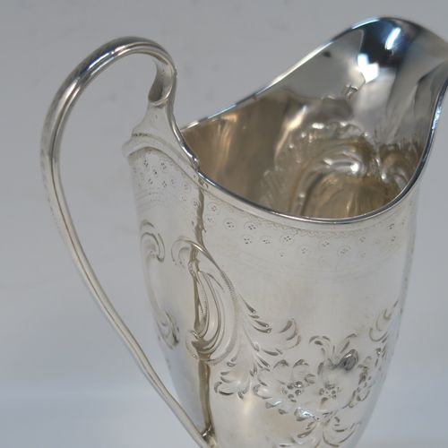 A very pretty Antique Georgian Sterling Silver cream jug, having a round body with tapering sides in a Helmet style, all hand-chased with floral and scroll decoration, a front cartouche with heraldic crest, a scroll handle, and sitting on a pedestal foot with a square base. This beautiful silver cream jug was made by John Denzilow of London in 1788. The dimensions of this fine hand-made antique silver cream jug are length 11.5 cms (4.5 inches), height 15 cms (6 inches), and it weighs approx. 137g (4.4 troy ounces).