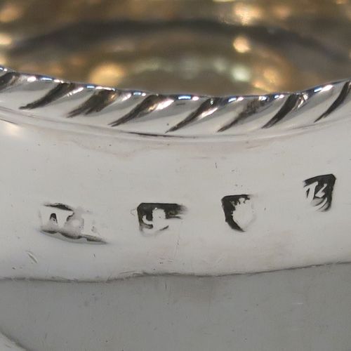 A very elegant Antique Georgian Sterling Silver cream jug, having a round bellied body with applied gadroon borders, a scroll side-handle, and all sitting on a round pedestal foot. This handsome silver cream or milk jug was made Walter Brind of London in 1762. The dimensions of this fine hand-made antique silver milk or cream jug are height 10 cms (4 inches), length 12 cms (4.75 inches), and it weighs approx. 127g (4 troy ounces).