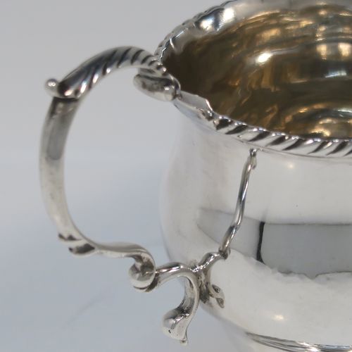 A very elegant Antique Georgian Sterling Silver cream jug, having a round bellied body with applied gadroon borders, a scroll side-handle, and all sitting on a round pedestal foot. This handsome silver cream or milk jug was made Walter Brind of London in 1762. The dimensions of this fine hand-made antique silver milk or cream jug are height 10 cms (4 inches), length 12 cms (4.75 inches), and it weighs approx. 127g (4 troy ounces).