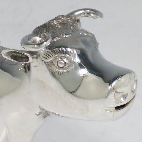An Antique Victorian Sterling Silver Dutch Cow cream jug, in a George II Cow creamer style, having a hinged lid with hand-chased flowers and an applied model of a bee, with a handle made from from the cows looped tail, and a spout made from the cows mouth, all sitting on four hoof feet. Made in ca. 1880 with Dutch hallmarks. The dimensions of this fine hand-made silver cow creamer are length 14.5 cms (5.75 inches), height 10 cms (4 inches), and it weighs approx. 126g (4 troy ounces).